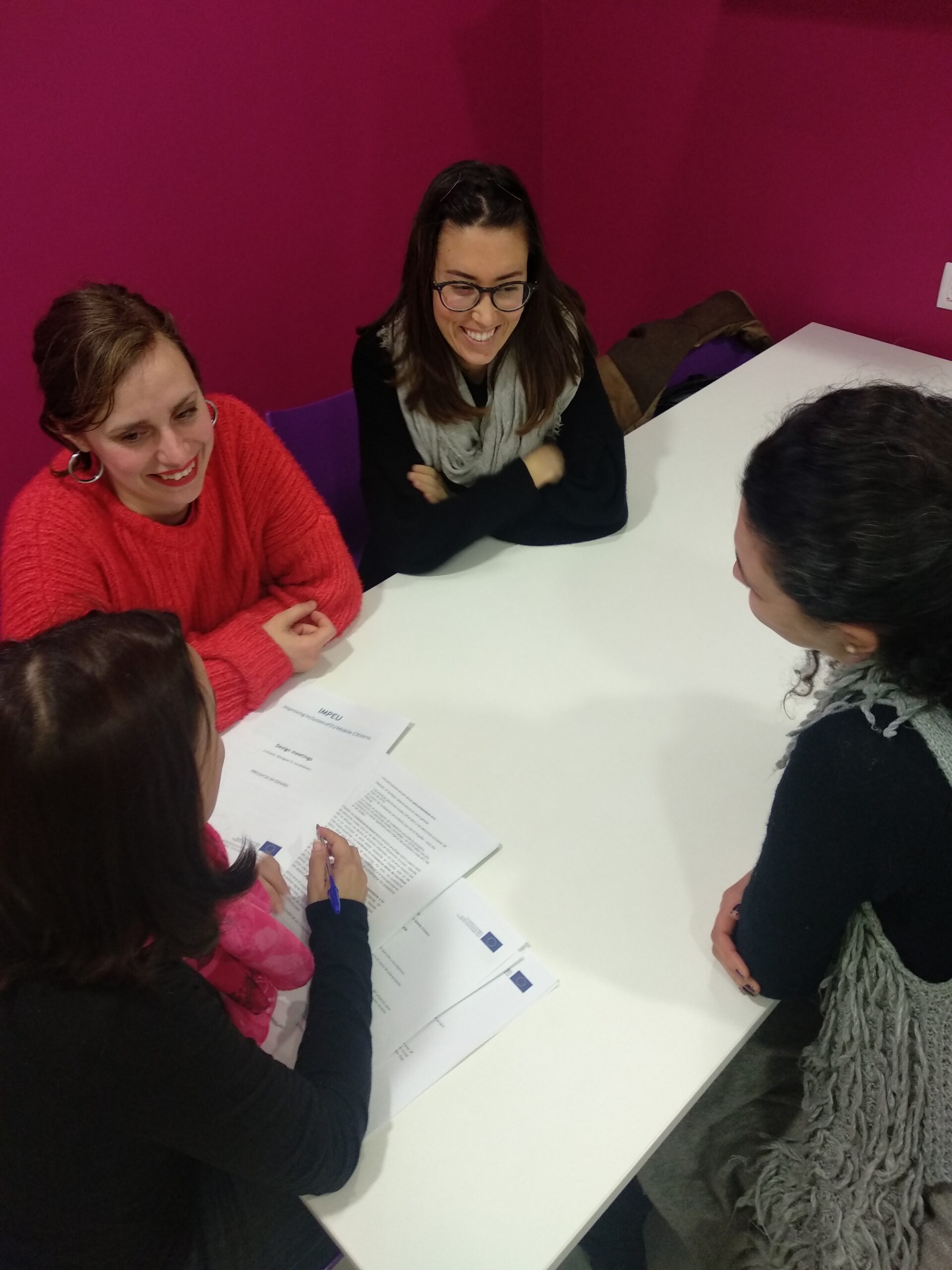 Mujeres empresarias en una sesión de mentoría grupal con documentos de fondos europeos, trabajando en equipo con Impulsa Europa