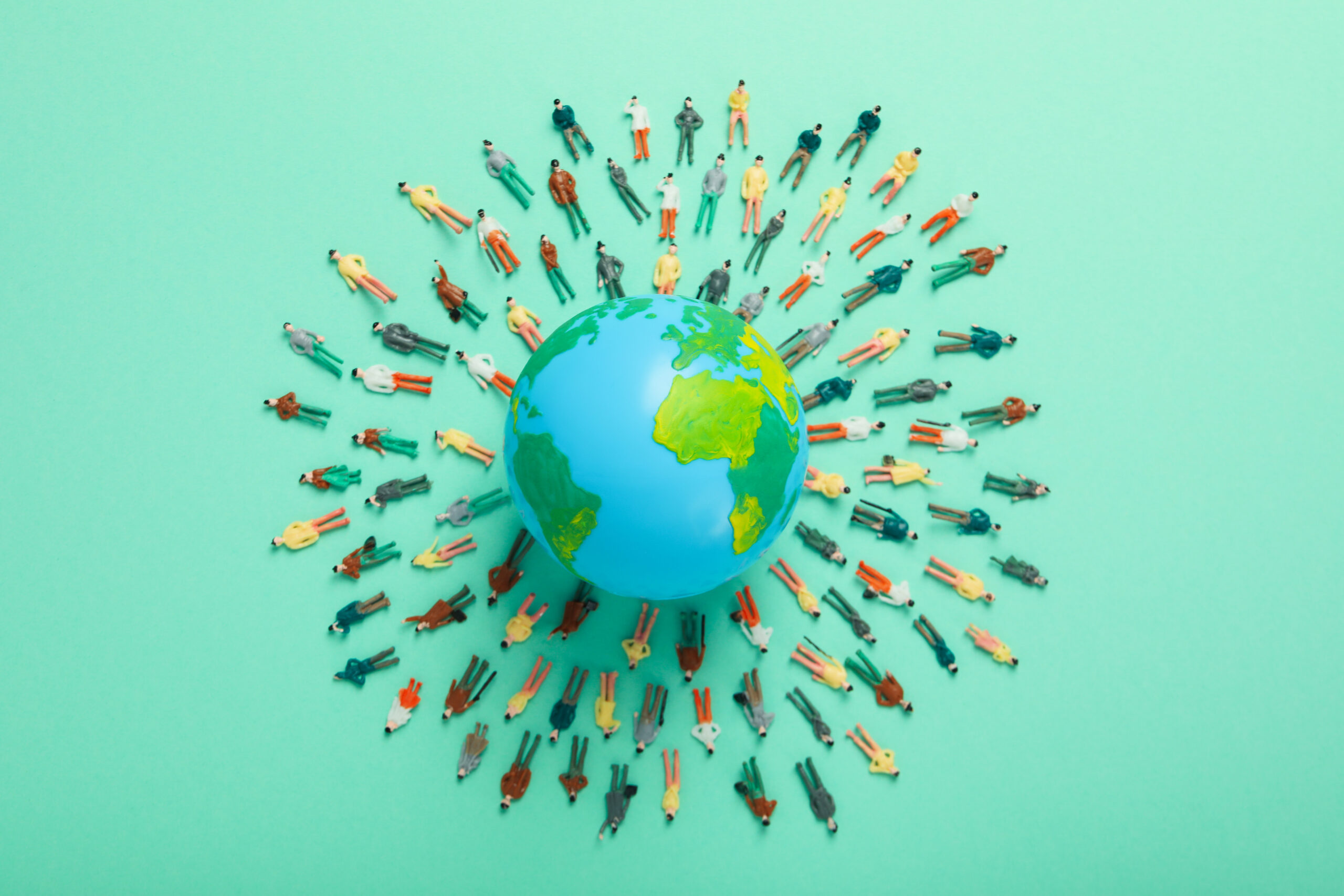 Personas rodeando un globo terráqueo, simbolizando la cooperación internacional en proyectos medioambientales del programa LIFE.